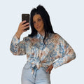 PINTONAS camisa satinada de manga larga con estampado floral en tonos azules y marrones, cuello camisero y lazada frontal.