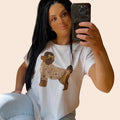 Camiseta blanca de PINTONAS con estampado de caniche marrón con un lazo dorado en la cabeza y un jersey estampado de flores.