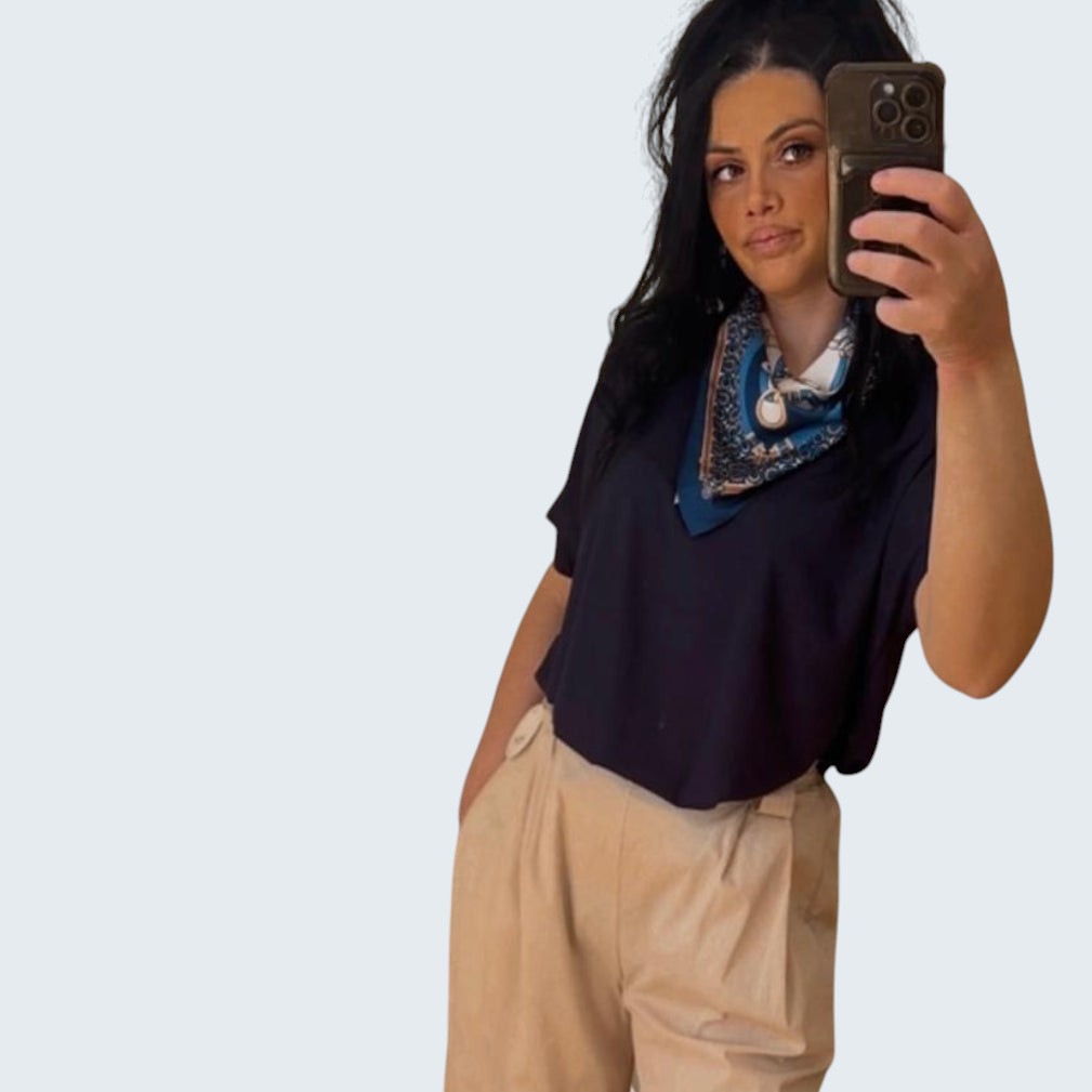 PINTONAS camiseta azul marino de manga corta con pañuelo estampado superpuesto y pantalón beige.