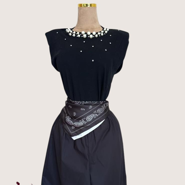 Camiseta negra PINTONAS sin mangas con hombreras y adornos de perlas y pedrería en el cuello.