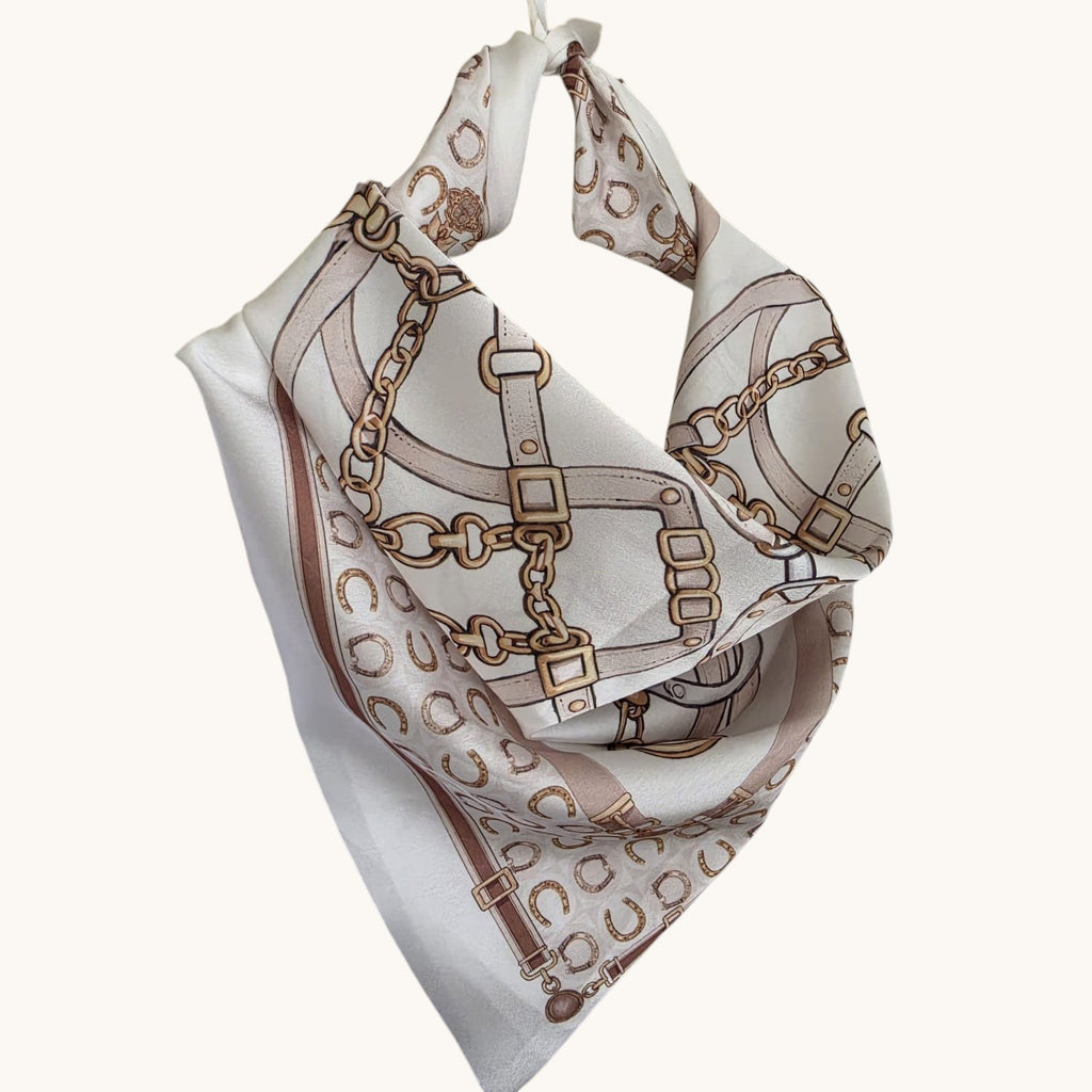 Pañuelo de seda PINTONAS con estampado de cadenas y herraduras en tonos beige y blanco.