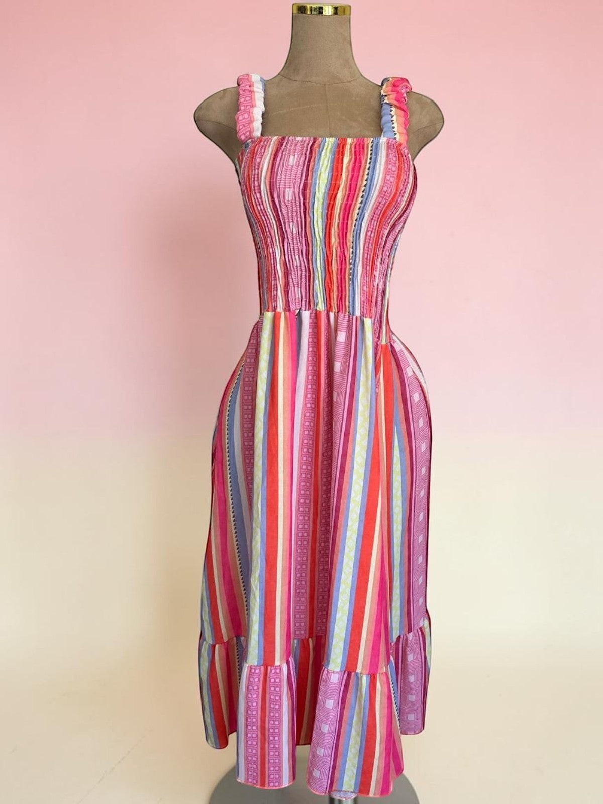 Vestido midi PINTONAS de rayas verticales multicolor con cuerpo fruncido nido de abeja y volante en el bajo. 50% Viscosa/50% Poliéster.