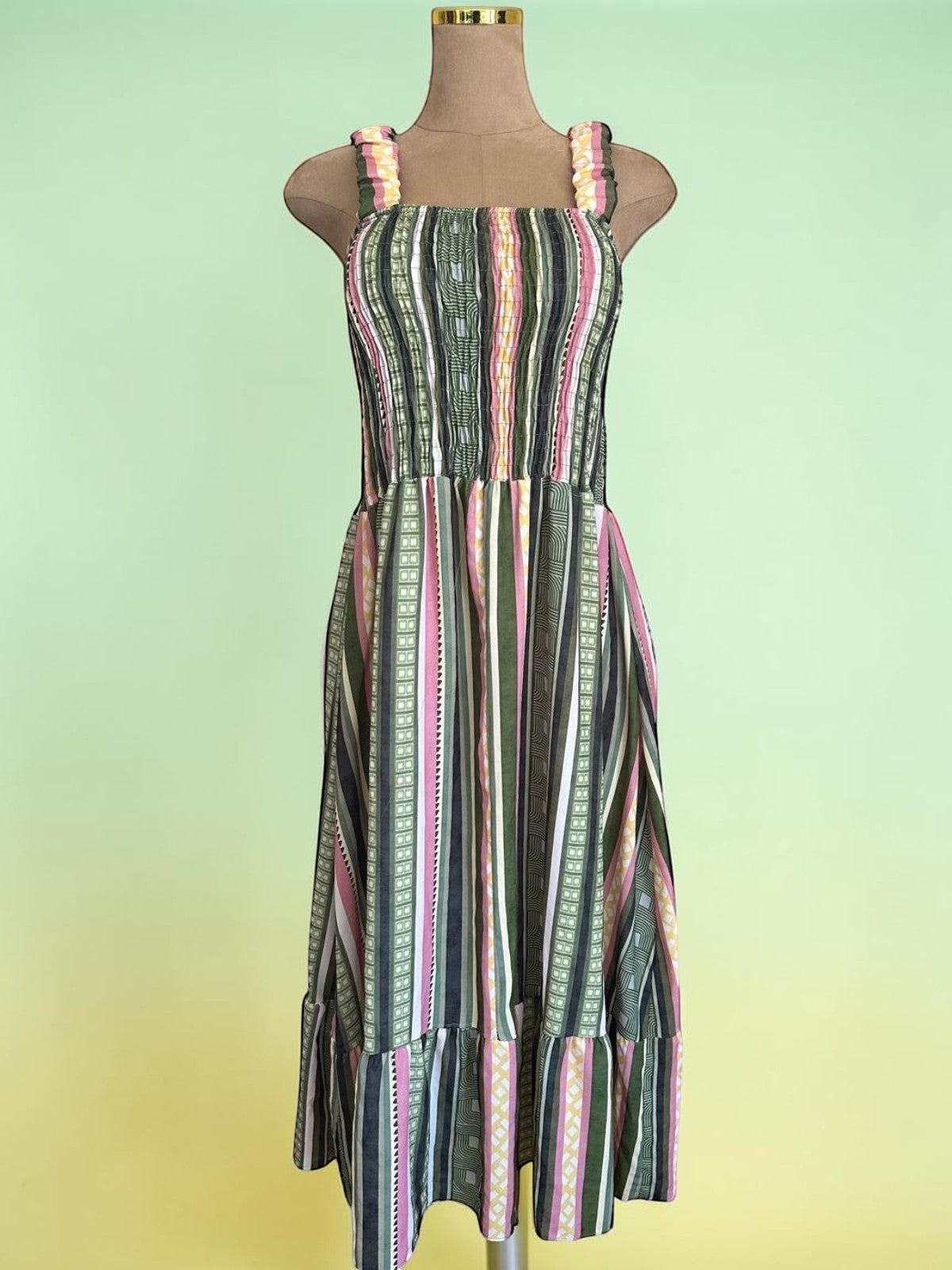 Vestido midi PINTONAS de rayas verticales en verde, rosa y amarillo. Cuerpo fruncido nido de abeja y falda con volante. 50% Viscosa / 50% Poliéster.