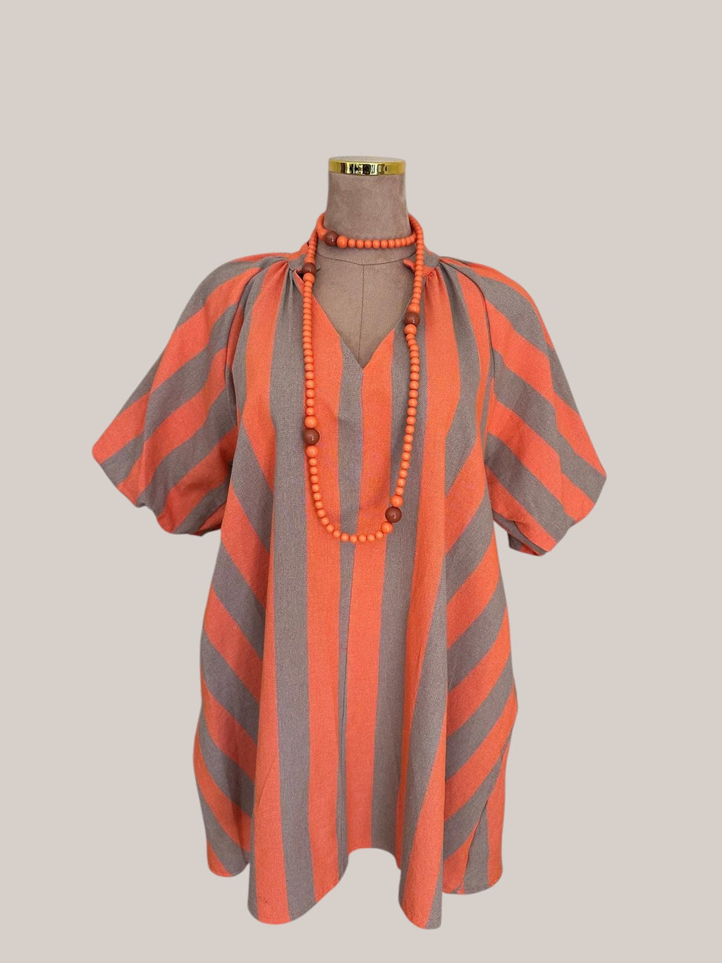 Vestido PINTONAS de rayas verticales en beige y naranja, con manga abullonada y escote en V.